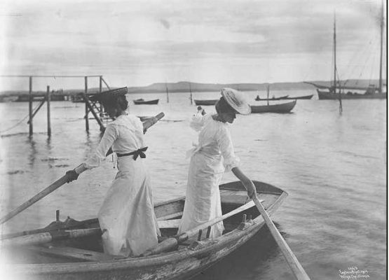 Kate og Agathe i robåt ved Sundestranda, den gamle badebryggen i bakgrunnen (Wilse, 1904)