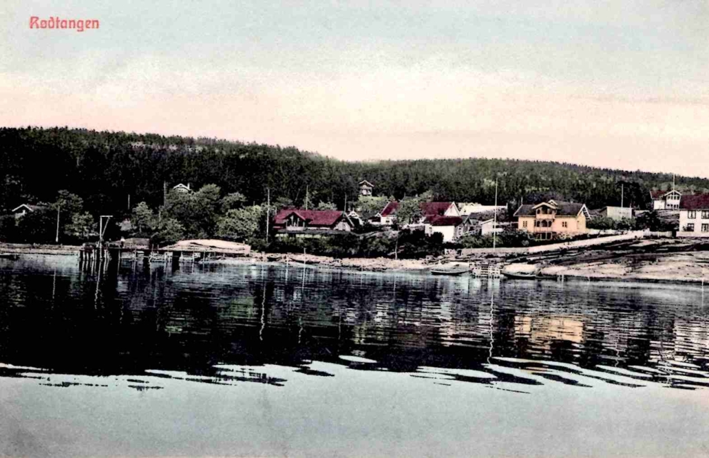 Håndkolorert foto fra cirka 1906, som viser deler av gamle Rødtangen sentrum sett fra fjorden. Hotellet er nyrenovert og utvidet med blant annet stor glassveranda.